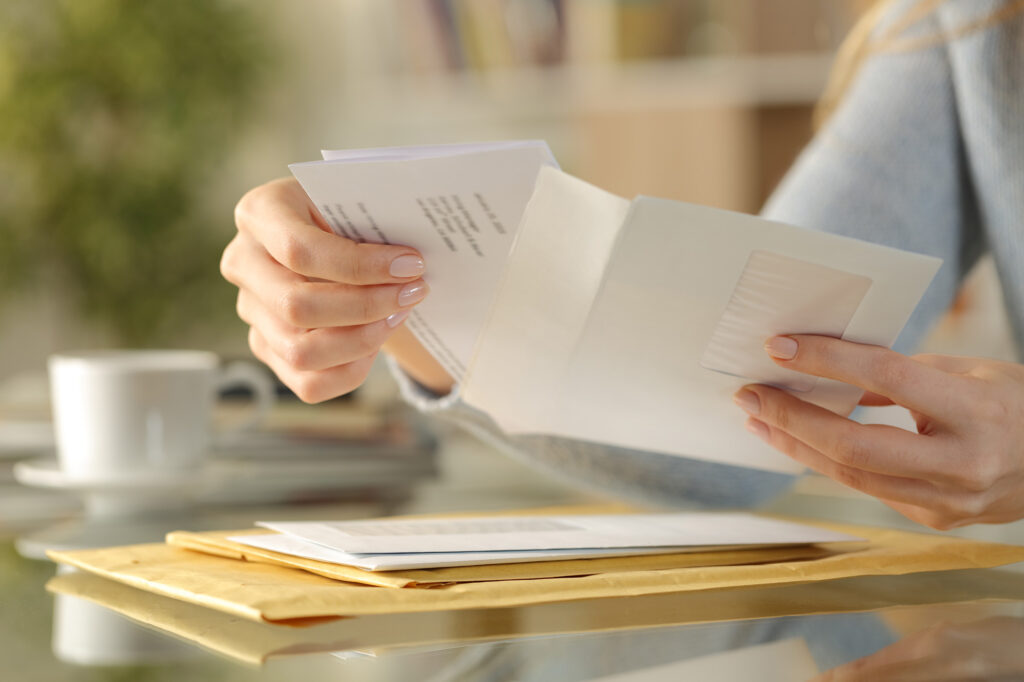 A person opening an envelope and other mail.